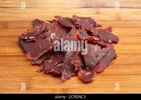 Mucchio di pastirma tradizionale turca a fette sottili (pastrami) su tagliere di legno con spazio di copia per il testo, primo piano Foto Stock