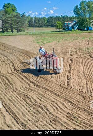 Otsego, Michigan - UN agricoltore di 90 anni guida un trattore Farmall Model M, sbarcando un campo in una piccola azienda agricola nel Michigan occidentale. Trebbiatrice internazionale Foto Stock