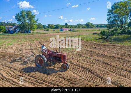 Otsego, Michigan - UN agricoltore di 90 anni guida un trattore Farmall Model M, sbarcando un campo in una piccola azienda agricola nel Michigan occidentale. Trebbiatrice internazionale Foto Stock