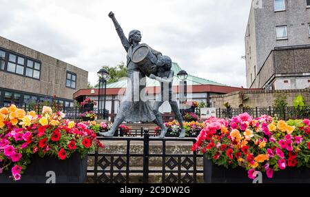 Jackie Crookston statua commemorativa (David Annand), Tranent, East Lothian, Scozia, Regno Unito con Keep Scotland Beautiful flowers Foto Stock