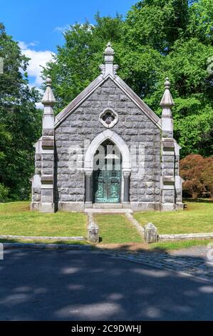 Mausoleo in pietra con simboli cristiani e cancello in ferro battuto con alberi sullo sfondo, al Sleepy Hollow Cemetery nell'Upstate NY Foto Stock