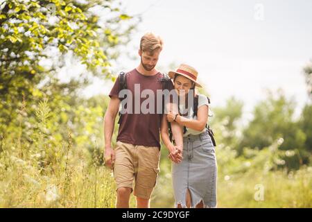 Escursione in coppia lungo Woodland Path. Felice amore uomo e donna in vacanza camminando insieme. Concetto di stile di vita attivo. I giovani che camminano con Foto Stock