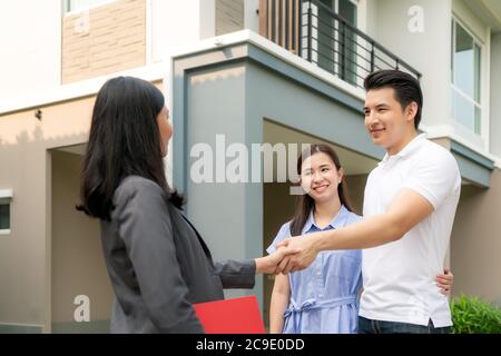 Felice coppia asiatica alla ricerca della loro nuova casa e agitare le mani con broker immobiliare dopo un accordo. Giovane coppia handshaking agente immobiliare dopo Foto Stock
