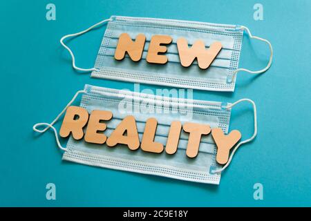 NUOVE parole DI REALTÀ sulle maschere facciali protettive su sfondo blu. Dopo covid-19 pandemie cambiamenti, nuova normale, indossare maschera viso in concetto pubblico. Foto Stock