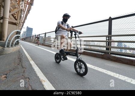New York City, Stati Uniti. 30 luglio 2020. Le vendite di biciclette e scooter sono aumentate vertiginosamente a New York City mentre la gente rimane fuori dai trasporti pubblici a causa della pandemia COVID-19, un uomo guida una bicicletta pieghevole lungo la strada esterna nord pedonale/ciclabile ed Koch Queensboro Bridge, condividendo la strada stretta con ciclisti e pedoni, New York, NY, luglio 30, 2020. (Anthony Behar/Sipa USA) Credit: Sipa USA/Alamy Live News Foto Stock