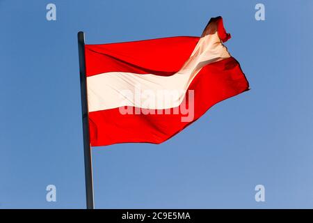 Bandiera austriaca sventolante nel cielo azzurro e senza nuvole. Austria Foto Stock