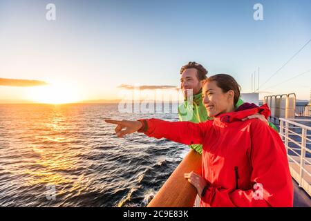 Crociera viaggio coppia di turisti che punta alla vista mare dal tour in traghetto. Donna asiatica persone multirazziali che viaggiano insieme al tramonto. Foto Stock