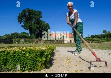 30 luglio 2020, Sassonia-Anhalt, Hundisburg: Giardiniere del paesaggio Anke Klaffehn erbacce in una broderie nel giardino barocco del Palazzo di Hundisburg. I primi edifici del Castello di Hundisburg furono già eretti nel XII secolo. Nel 1452 la famiglia von Alvensleben acquisì il complesso. Johann Friedrich von Alvensleben fece convertire l'Hundisburg in un palazzo barocco e stese il giardino barocco dell'architetto di Stato Braunschweig Hermann Korb alla fine del XVII secolo. Il Palazzo di Hundisburg e il giardino barocco fanno parte della rete 'Garden Dreams - Parchi storici in Sassonia-Anhalt' che ce Foto Stock