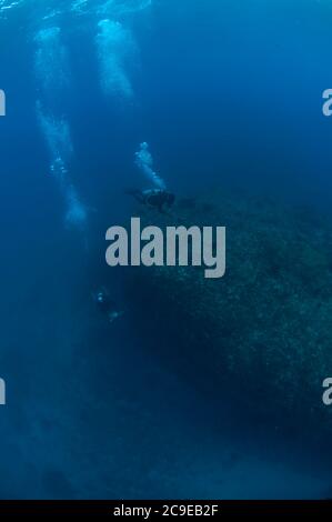 I subacquei nuotano oltre la roccia, il sito di immersione Pintu Kota, Ambon, Indonesia, Oceano Pacifico Foto Stock