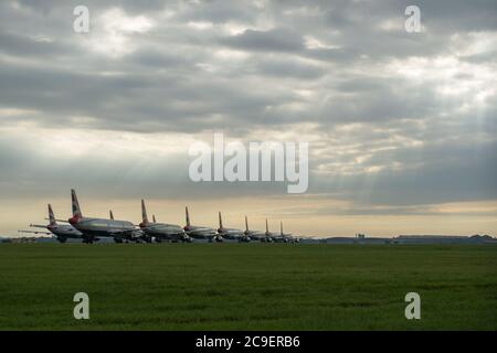 Glasgow, Scozia, Regno Unito. 31 luglio 2020. Nella foto: I raggi solari si infrangono attraverso le nuvole che brillano sulla collezione di aeromobili airbus British Airways (BA) con messa a terra delle varianti A319, A320 e A321 che sono collegati a terra all'aeroporto di Glasgow. Da quando la pandemia del coronavirus (COVID-19) ha colpito il Regno Unito, British Airways ha assimato un quarto del suo personale, e ha ritirato l'intera flotta di aeromobili Boeing 747 in un tentativo di ridurre i costi. Credit: Colin Fisher/Alamy Live News Foto Stock