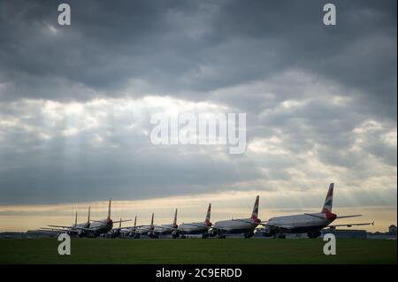 Glasgow, Scozia, Regno Unito. 31 luglio 2020. Nella foto: I raggi solari si infrangono attraverso le nuvole che brillano sulla collezione di aeromobili airbus British Airways (BA) con messa a terra delle varianti A319, A320 e A321 che sono collegati a terra all'aeroporto di Glasgow. Da quando la pandemia del coronavirus (COVID-19) ha colpito il Regno Unito, British Airways ha assimato un quarto del suo personale, e ha ritirato l'intera flotta di aeromobili Boeing 747 in un tentativo di ridurre i costi. Credit: Colin Fisher/Alamy Live News Foto Stock