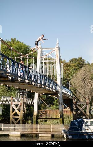 Ragazzi che saltano dal ponte pedonale Teddington Lock nel Tamigi, Teddington, Inghilterra, Regno Unito Foto Stock