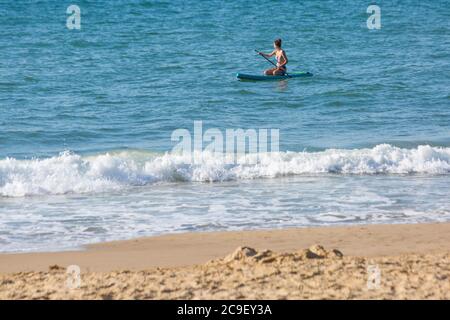 Poole, Dorset UK. 31 luglio 2020. Tempo nel Regno Unito: Giornata calda e soleggiata alle spiagge di Poole, con l'aumento delle temperature e gli amanti del sole si affollano verso il mare per godersi il tempo soleggiato in quello che si prevede sia il giorno più caldo dell'anno, arrivarci presto per ottenere un buon posto prima che diventa più affollato. Nemmeno le 9 e già le spiagge sono sempre affollate e i parcheggi si riempiono. Il paddle boarder mantiene fresco il mare. Credit: Carolyn Jenkins/Alamy Live News Foto Stock