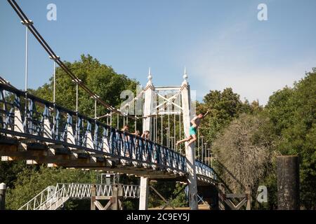 Ragazzi che saltano dal ponte pedonale Teddington Lock nel Tamigi, Teddington, Inghilterra, Regno Unito Foto Stock