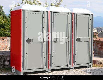 tre cabine per servizi igienici portatili installate in un parco pubblico della città e una grande cabina per disabili Foto Stock