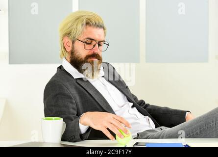 Business manager rilassante. Lavoro in ufficio. Concetto aziendale. Hipster giocare a tennis palla. Burnout e mancanza di idee. Concetto di crisi. Uomo imprenditore di successo formale abito da lavoro seduta interni ufficio. Foto Stock