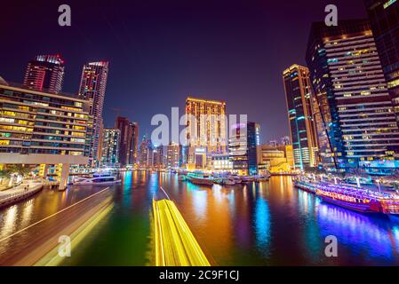 Dubai Marina di notte con grattacieli, barche e riflessi in acqua, Emirati Arabi Uniti Foto Stock