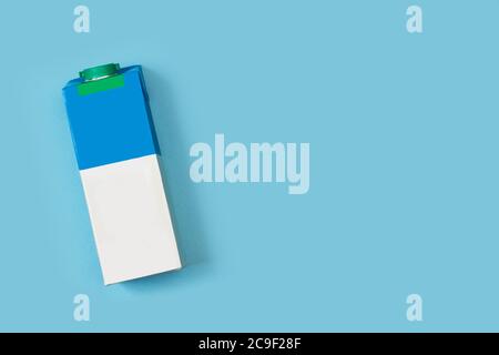 Un mattone di latte bianco e azzurro su una luce sfondo blu Foto Stock