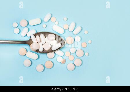 Pillole mediche su un cucchiaio su uno sfondo azzurro chiaro in una vista dall'alto Foto Stock