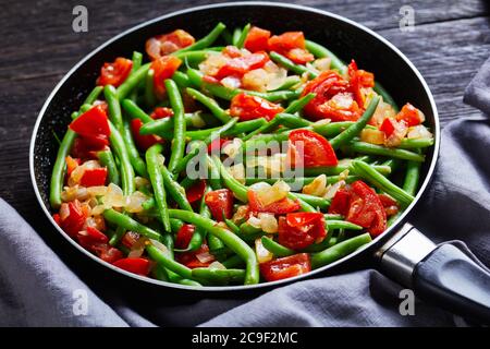 Fagioli verdi fritti con cipolle e pomodori Foto Stock