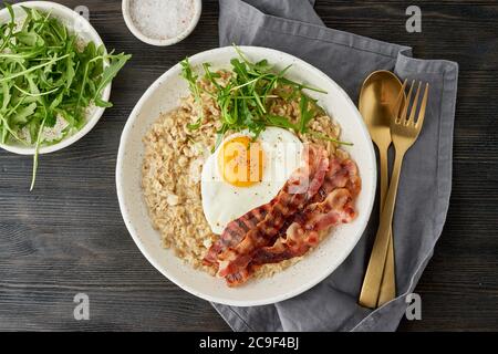 Farinata d'avena, uova fritte e pancetta fritta. Equilibrio di proteine, grassi, carboidrati. Primo piano Foto Stock