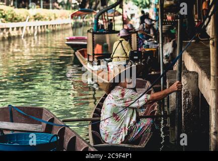 Venditore di donne thailandesi che vende frutta e verdura al mercato galleggiante di Taling Chan vicino a Bangkok, Thailandia. Foto Stock