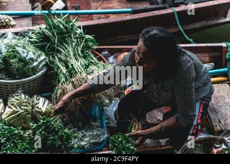 Venditore di donne thailandesi che vende frutta e verdura al mercato galleggiante di Taling Chan vicino a Bangkok, Thailandia. Foto Stock