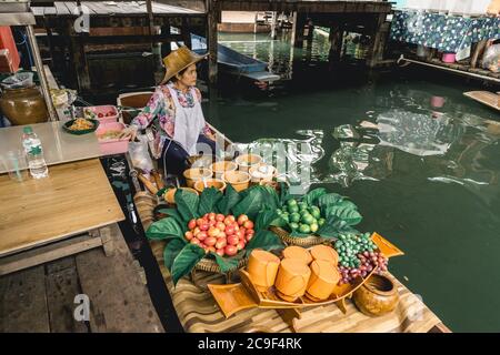 Venditore di donne thailandesi che vende frutta e verdura al mercato galleggiante di Taling Chan vicino a Bangkok, Thailandia. Foto Stock