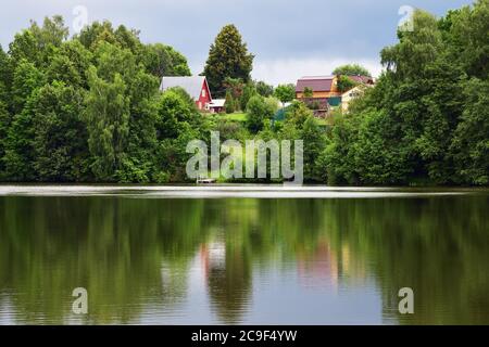 Estate pittoresco paesaggio rustico con piccolo villaggio sulla riva del lago in prima mattina. Paesaggio di campagna. Russia Foto Stock