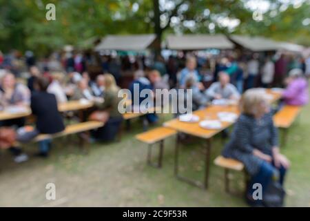 I tavoli e le sedie affollati e offuscati con le persone che chiacchierano nel parco in Svezia Foto Stock