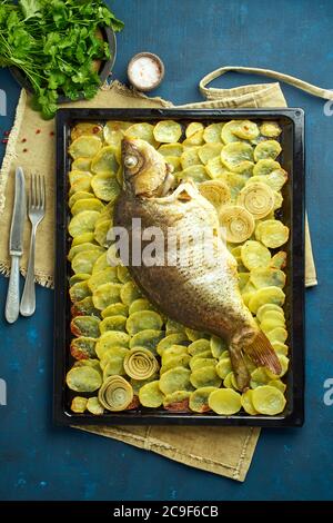 Carpa cotta, pesce intero dal forno con patate a fette su un grande vassoio piatto di pasta tradizionale Foto Stock