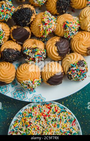 Biscotti al burro disposti su un piatto accanto a spruzzi colorati Foto Stock