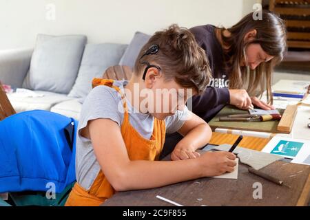 Ragazzo con impianto cocleare e sua madre donna imparare linocutting al laboratorio di stampa in una classe d'arte in Galles del Carmarthenshire Regno Unito KATHY DEWITT Foto Stock