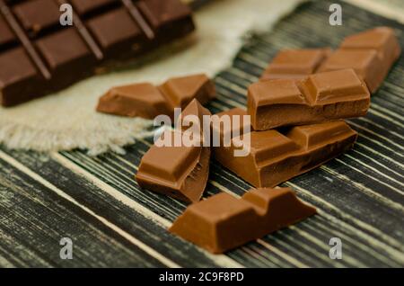 Gruppo di barrette di cioccolato di diversi colori. Dolci assortiti di vario genere. Cioccolato assortito su rustico sfondo di legno Foto Stock