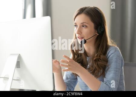 Operatore di call center femminile con cuffie e auricolari che parla con il cliente Foto Stock