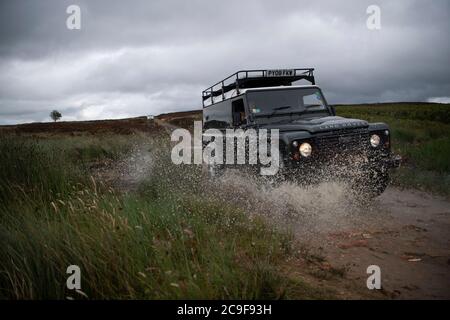 North Yorkshire Moors, UK - Luglio 23 2020: Land Rover Defender fuori strada su una corsia verde nel North Yorkshire Moors in Inghilterra. Foto Stock