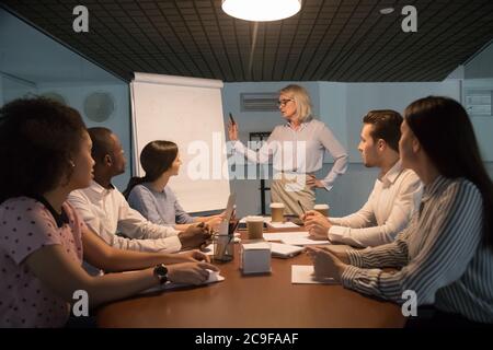 Donna d'affari matura che tiene il briefing, facendo la presentazione della lavagna a fogli mobili Foto Stock