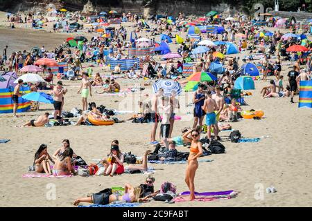 La gente sulla spiaggia di Barry Island, come primo ministro per il Galles, Mark Drakeford, ha annunciato che da lunedì fino a 30 persone possono incontrarsi all'esterno mantenendo le distanze sociali nell'ultimo allentamento delle misure di coronavirus in Galles. Foto Stock