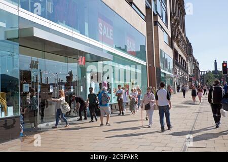 Edimburgo, Scozia, Regno Unito. 31 Gianni 2020. Giorno caldo a Edimburgo 22 gradi centigradi entro mezzogiorno con sole frizzante per i turisti e residenti che visitano il centro della città per fare acquisti nelle vendite. Pictued: Persone in attesa di una coda per l'apertura del negozio. Foto Stock