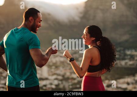 Una coppia di fitness che dà un pugno dopo l'allenamento. L'uomo e la donna atletica festeggiano dopo una corsa. Foto Stock