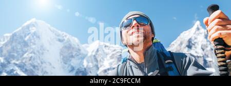 Ritratto di sorridente Hiker su Taboche 6495m e Cholatse 6440m cime sfondo con bastoni da trekking, occhiali da sole UV protezione. Lui che gode di montagna Foto Stock