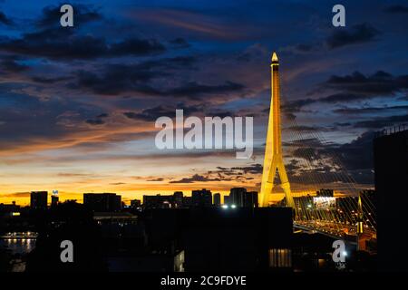 Rama VIII illuminato Ponte (Rama 8. Ponte), un ponte sospeso che attraversa il fiume Chao Phraya a Bangkok, Thailandia, durante un tramonto colorato Foto Stock