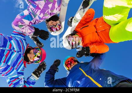 Quattro ragazze teenage guardano giù con lo sci ed il vestito di sport di inverno che si levano in piedi insieme sorridente Foto Stock