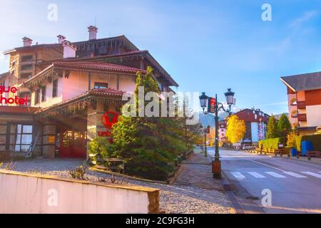 Bansko, Bulgaria - 23 novembre 2019: Vista autunnale di via Pirin con case, alberi colorati e montagne Pirin Foto Stock