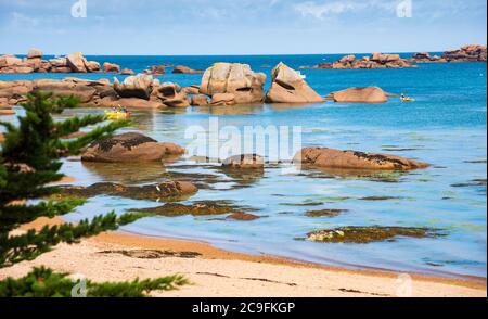 Persone kayak tra formazioni rocciose uniche a Pink Granite Coast vicino Tregastel. Cotes-D'armor, Bretagna, Francia Foto Stock