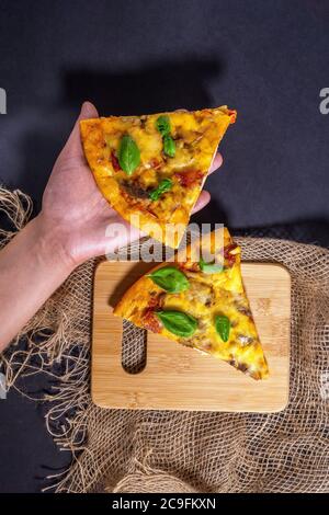 Due fette di foglie di basilico per pizza su sfondo nero, vista dall'alto. Disposizione piatta. Spazio per copiare il testo Foto Stock