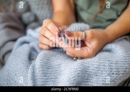 Primo piano delle mani femminili con maglia. Aghi per maglieria in metallo. Tessuto a maglia blu. Foto Stock