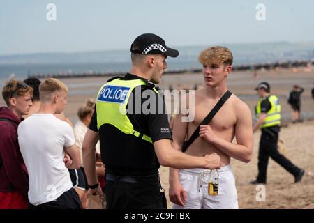 Edimburgo, Scozia, Regno Unito. 31 luglio 2020. La temperatura di 25°C e il sole hanno portato enormi folle a Portobello Beach fuori Edimburgo. Molti grandi gruppi di adolescenti stavano godendo la spiaggia e le bevande alcoliche erano molto popolari. Nella foto, intorno alle 15:00 si sono verificati problemi tra i giovani sulla spiaggia e i rinforzi della polizia sono stati rapidamente in scena e molte persone sono state rapite. Westbank Street è stata chiusa al traffico e circa 30 poliziotti stanno pattugliando la passeggiata. La polizia confisca l'alcool degli adolescenti che rimangono sulla spiaggia. Iain Masterton/Alamy Live News Foto Stock