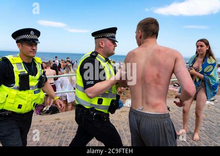 Edimburgo, Scozia, Regno Unito. 31 luglio 2020. La temperatura di 25°C e il sole hanno portato enormi folle a Portobello Beach fuori Edimburgo. Molti grandi gruppi di adolescenti stavano godendo la spiaggia e le bevande alcoliche erano molto popolari. Nella foto, intorno alle 15:00 si sono verificati problemi tra i giovani sulla spiaggia e i rinforzi della polizia sono stati rapidamente in scena e molte persone sono state rapite. Westbank Street è stata chiusa al traffico e circa 30 poliziotti stanno pattugliando la passeggiata. La polizia confisca l'alcool degli adolescenti che rimangono sulla spiaggia. Iain Masterton/Alamy Live News Foto Stock