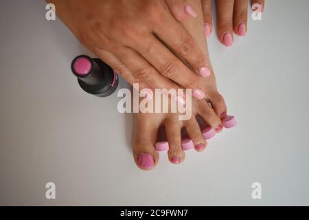 Piede femminile con pedicure, mettendo smalto rosa unghie sui chiodi dei piedi e delle mani Foto Stock